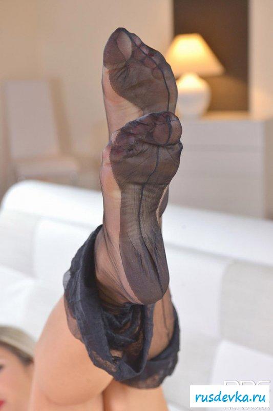 Женщина снимает чулки на диване